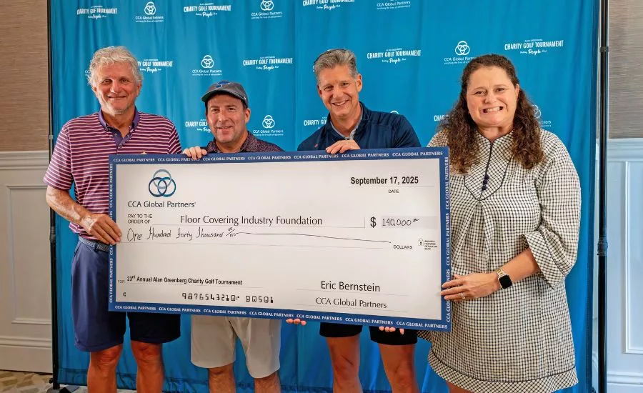 four people hold up a large check