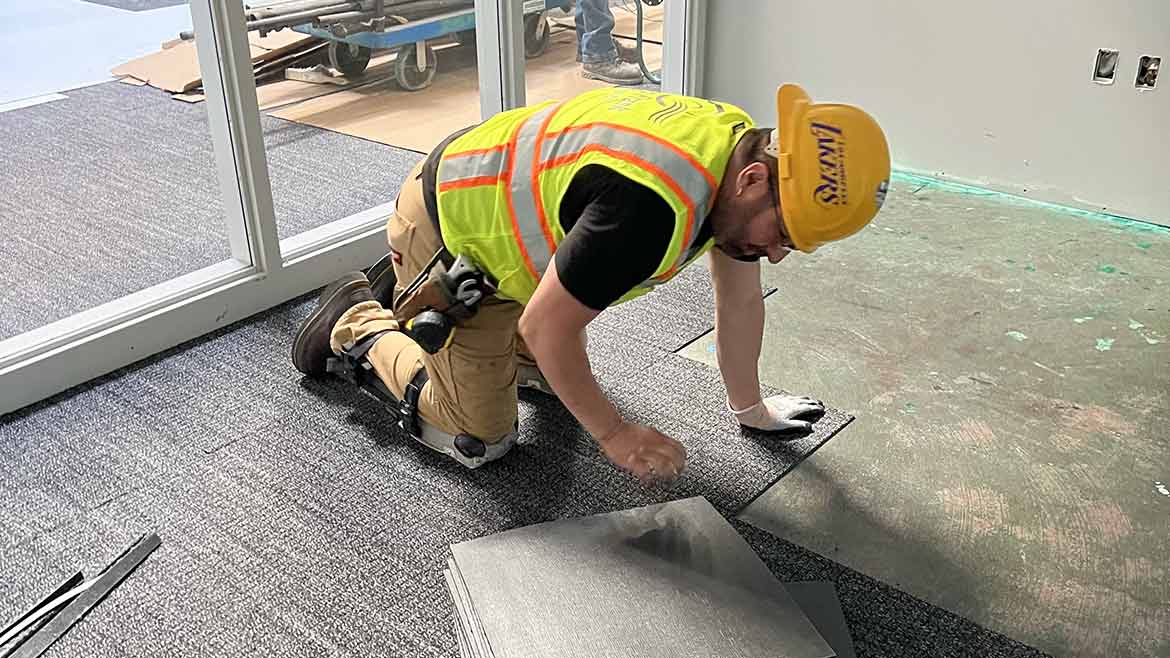 Edgar Diaz installing carpet tile