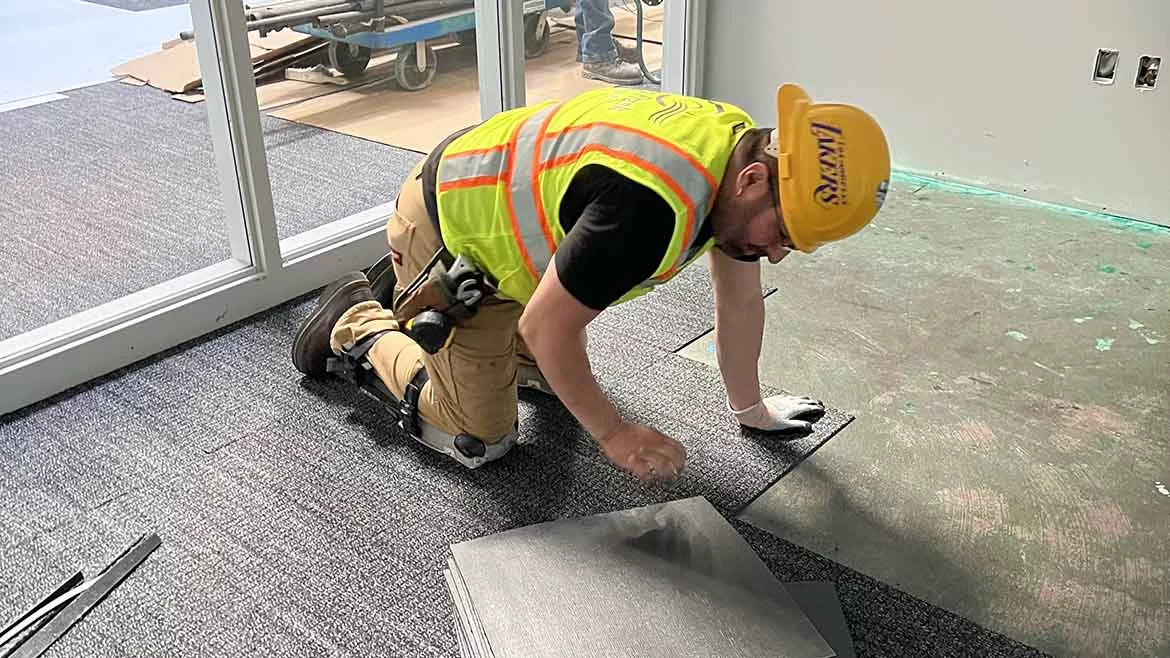 Edgar Diaz installing carpet tile